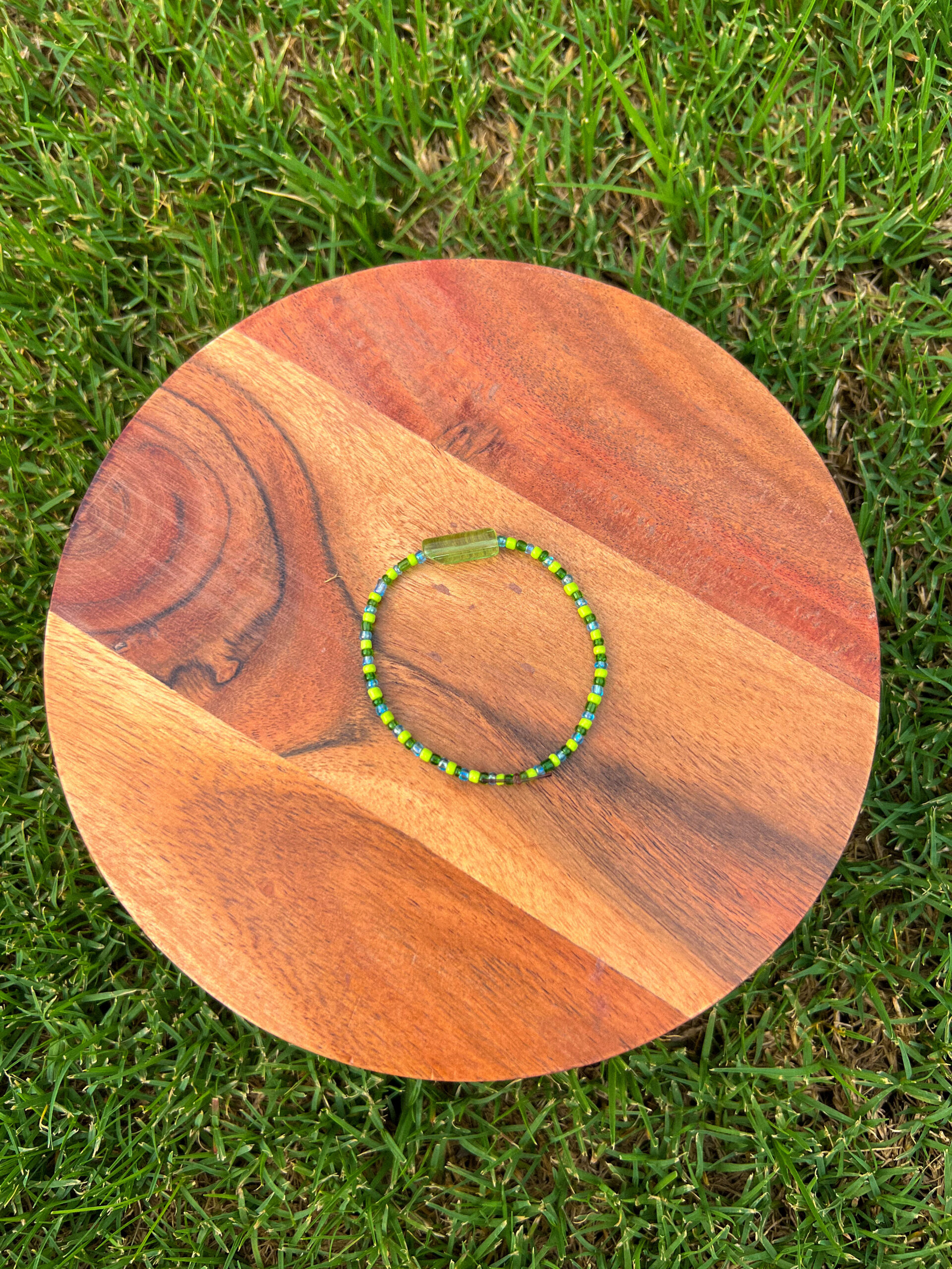 The Earth Bracelet with lime green, dark green, and blue beads surround a green accent bead.
