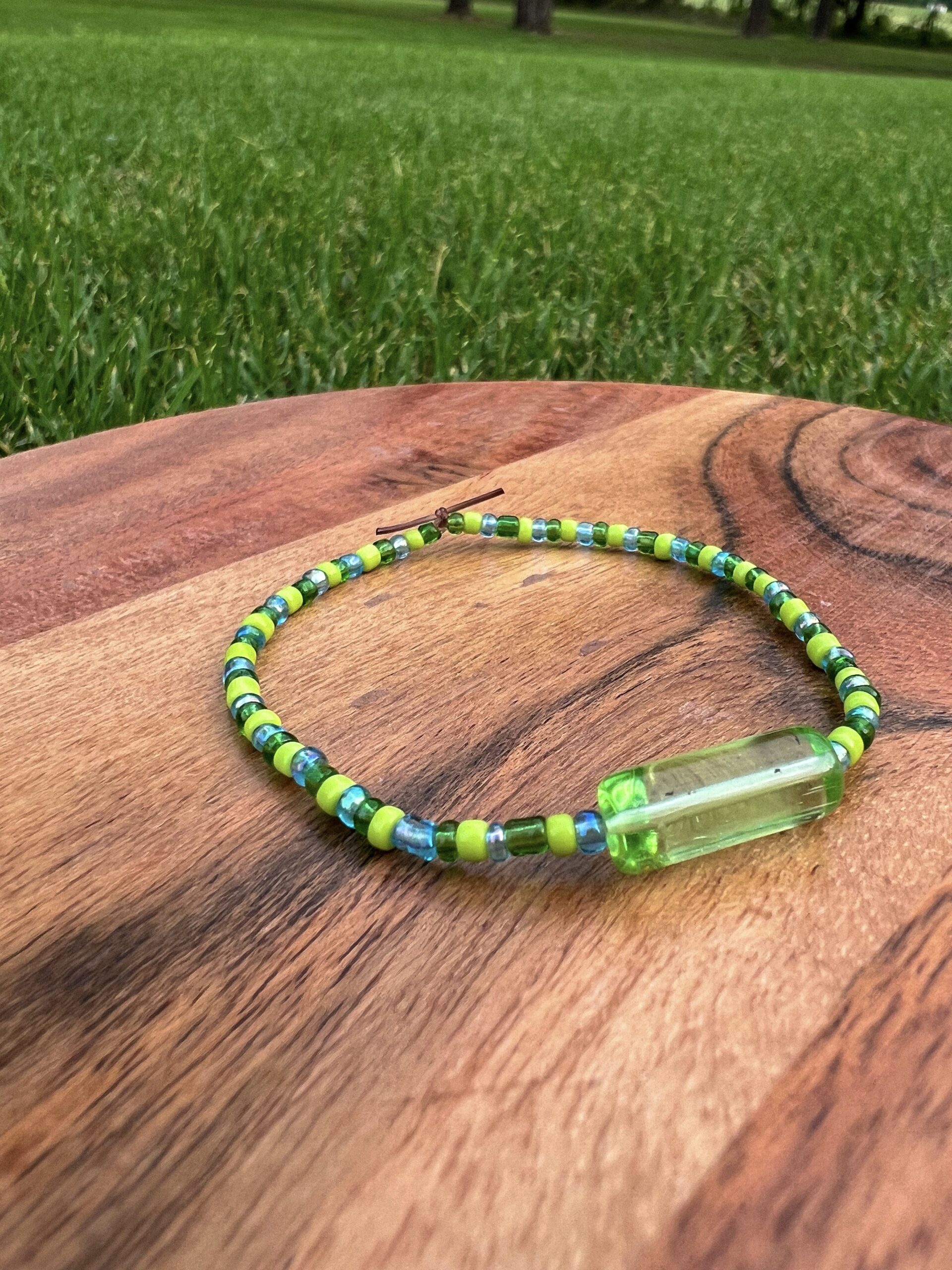 The Earth Bracelet with lime green, dark green, and blue beads surround a green accent bead.