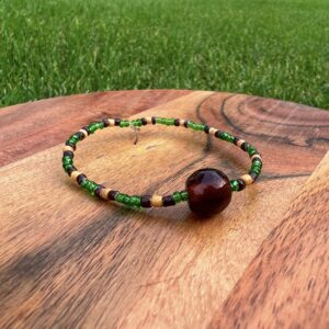 The Wildlife Conservation Bracelet with dark green, tan and brown beads surround a dark brown accent bead.