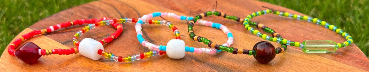 Five beaded bracelets with different colors sitting on a wooden platform.